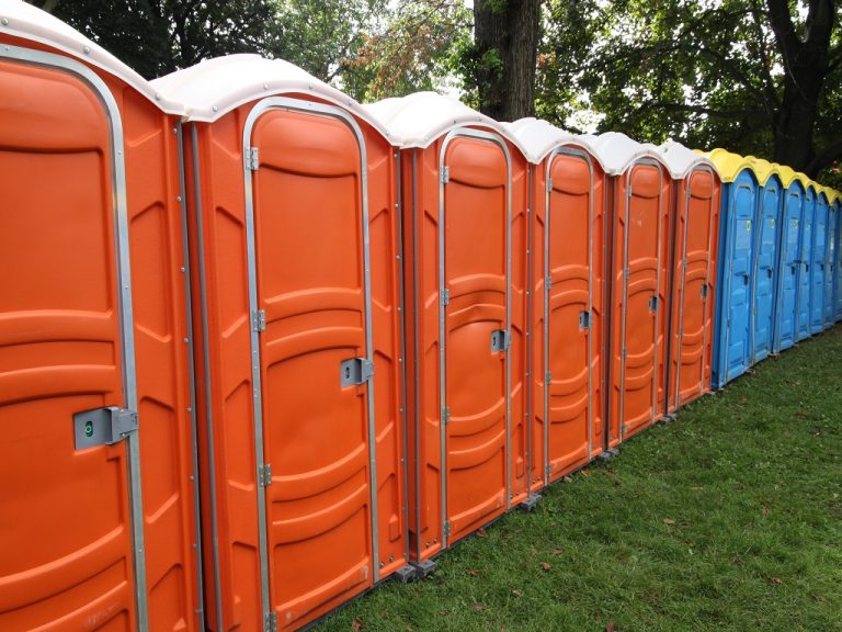 Colorful outdoor sanitation facilities set up in a park for the use of visitors to an outdoor festival.